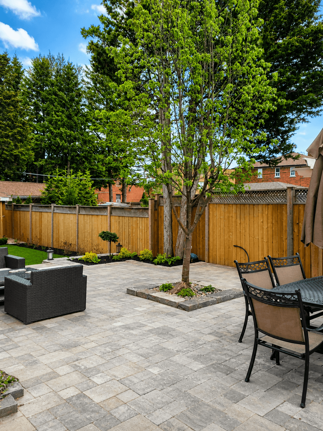 Backyard paver patio with patio furniture and feature tree well